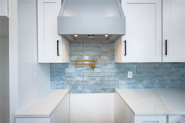 kitchen with white cabinetry, custom exhaust hood, decorative backsplash, and light stone countertops