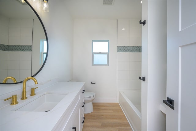 full bathroom with toilet, vanity, wood-type flooring, and tiled shower / bath