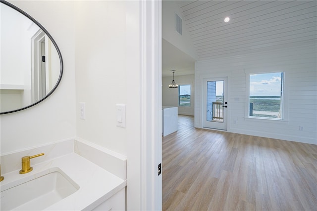 bathroom with hardwood / wood-style floors, lofted ceiling, a healthy amount of sunlight, and vanity