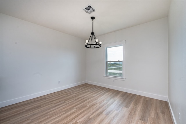 unfurnished room with light hardwood / wood-style floors and a chandelier