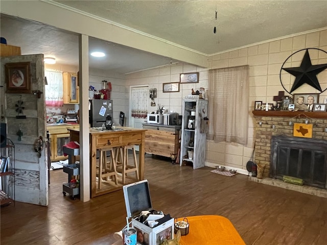 living room with ornamental molding, a workshop area, a textured ceiling, dark wood-type flooring, and a brick fireplace