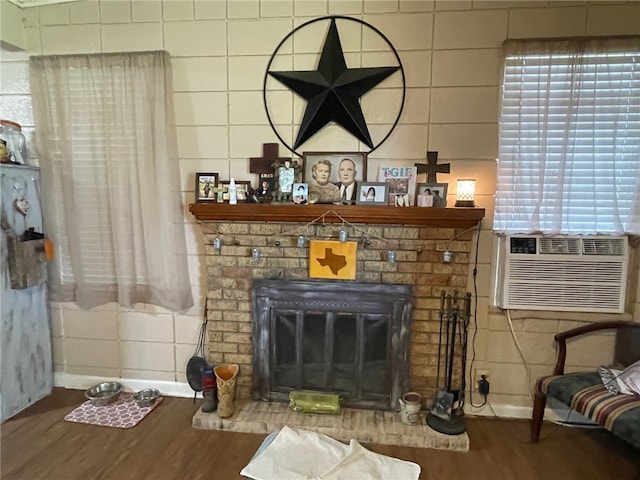 living room featuring a brick fireplace, a wealth of natural light, wood-type flooring, and cooling unit