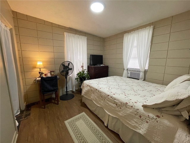 bedroom featuring hardwood / wood-style flooring, cooling unit, and tile walls