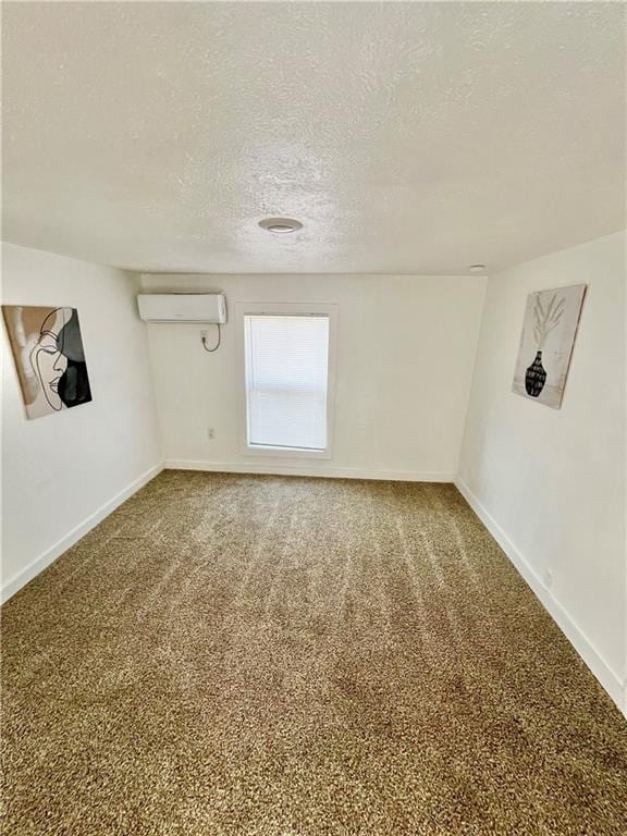 carpeted spare room featuring a textured ceiling, baseboards, and a wall mounted AC