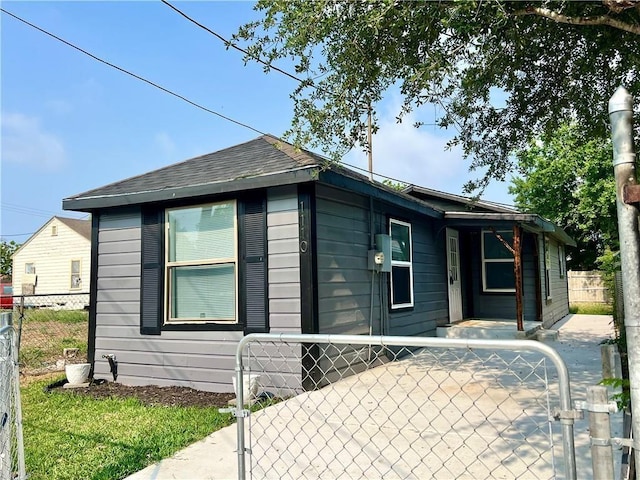 view of front of home featuring a fenced front yard, a gate, and roof with shingles