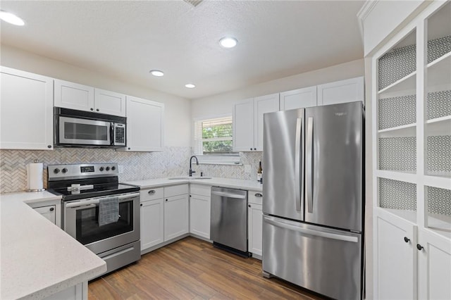 1010 Weber Pkwy, Corpus Christi, TX 78411 - kitchen featuring appliances with stainless steel finishes, dark wood-style flooring, decorative backsplash, white cabinetry, and recessed lighting