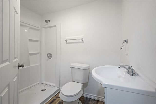 bathroom with hardwood / wood-style flooring, walk in shower, toilet, and sink