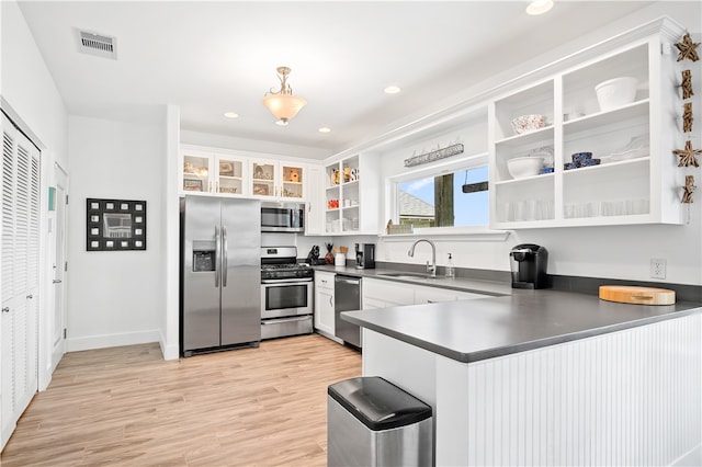 kitchen with hanging light fixtures, sink, white cabinetry, light wood-type flooring, and appliances with stainless steel finishes