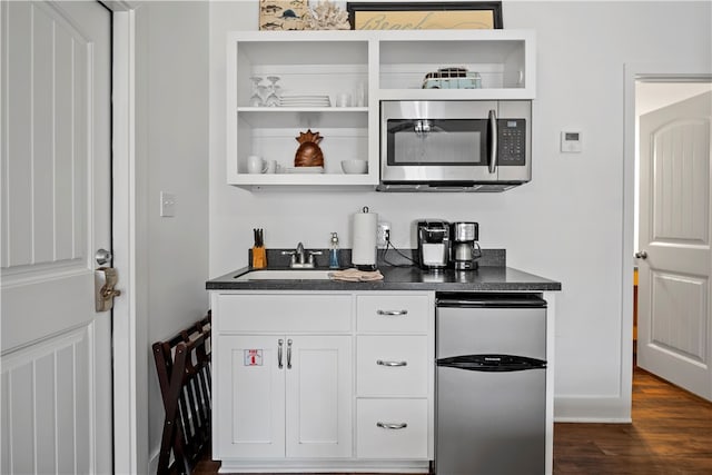 bar with dark hardwood / wood-style flooring, white cabinets, sink, and stainless steel appliances