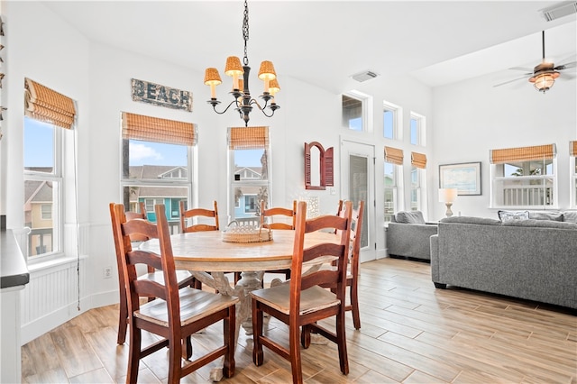 dining area with light hardwood / wood-style floors and ceiling fan with notable chandelier