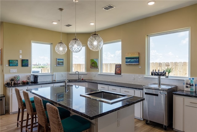 kitchen with dark stone countertops, light wood-type flooring, decorative light fixtures, and a center island