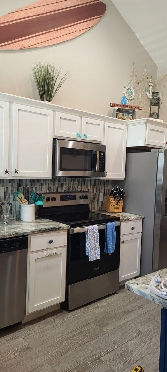 kitchen featuring light hardwood / wood-style floors, white cabinets, tasteful backsplash, light stone countertops, and appliances with stainless steel finishes