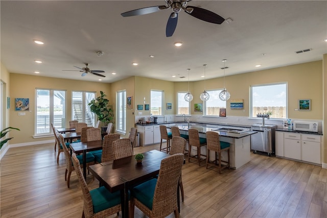 dining space with ceiling fan, plenty of natural light, sink, and light wood-type flooring