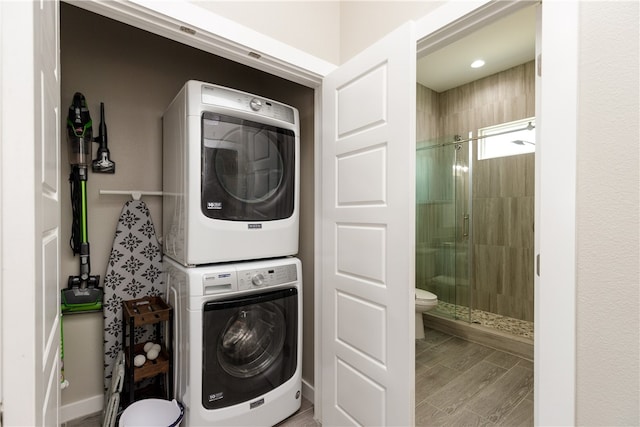 washroom with hardwood / wood-style flooring and stacked washer / drying machine