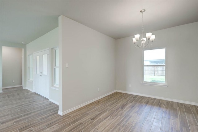 empty room featuring lofted ceiling and an inviting chandelier