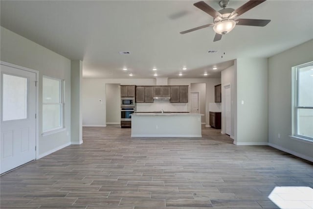 kitchen with ceiling fan, stainless steel appliances, a kitchen island with sink, and sink