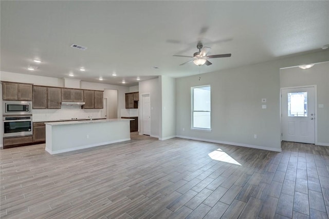 kitchen featuring stainless steel appliances, a center island with sink, ceiling fan, and sink