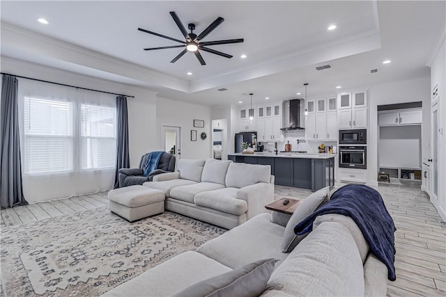 living room featuring ceiling fan and a tray ceiling