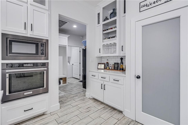 kitchen featuring separate washer and dryer, appliances with stainless steel finishes, backsplash, and white cabinetry