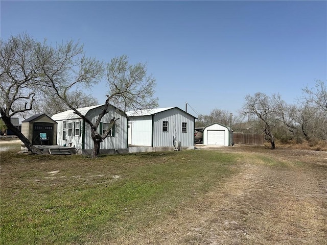 exterior space with a detached garage, fence, an outdoor structure, driveway, and a yard