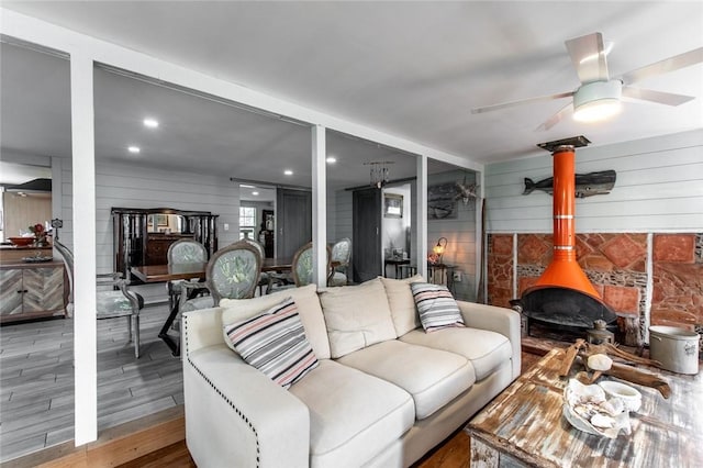 living room with ceiling fan, wood finished floors, a wood stove, and recessed lighting