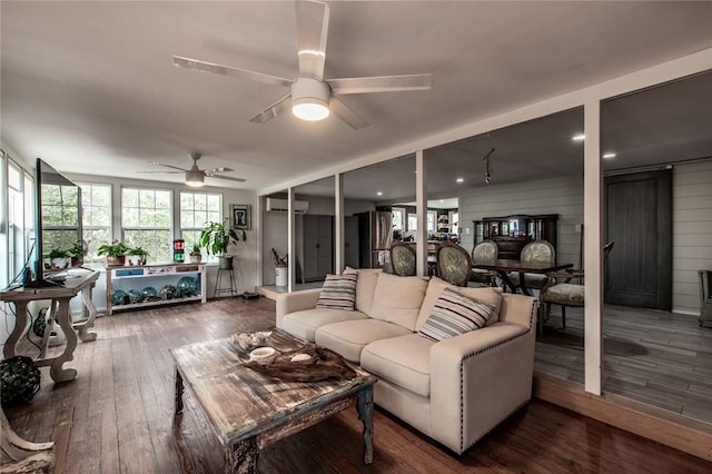 living area with an AC wall unit, hardwood / wood-style flooring, and a ceiling fan