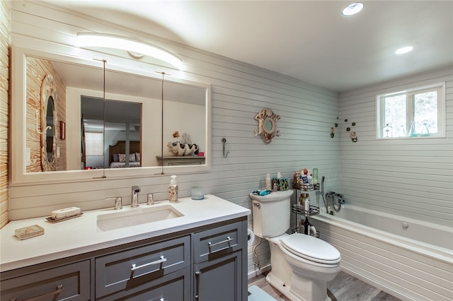 full bath featuring vanity, wood finished floors, a bathtub, and toilet