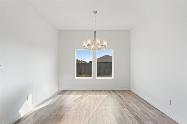 unfurnished room with a chandelier and light hardwood / wood-style floors