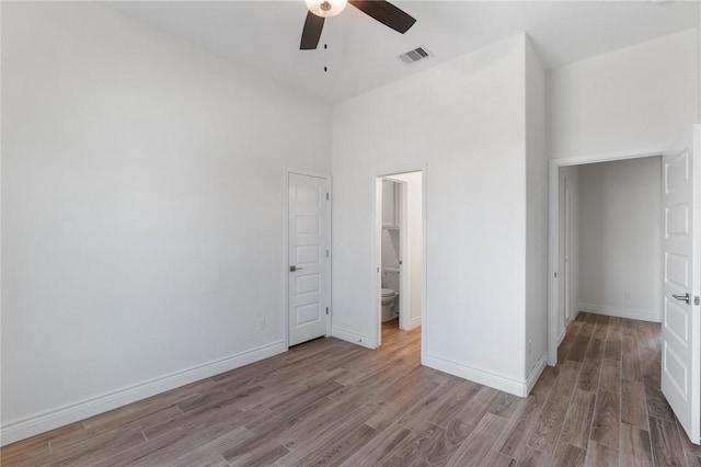 unfurnished bedroom with ceiling fan, a closet, a towering ceiling, and light hardwood / wood-style floors