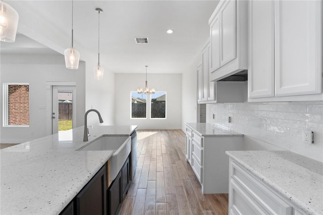 kitchen with pendant lighting, light stone counters, and white cabinetry