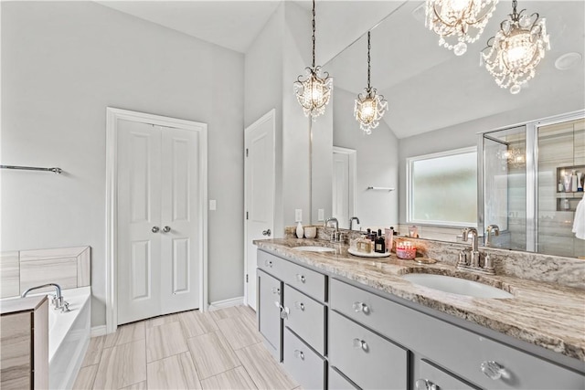 bathroom featuring vanity, an inviting chandelier, shower with separate bathtub, and vaulted ceiling