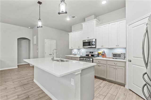 kitchen featuring white cabinets, appliances with stainless steel finishes, an island with sink, and sink