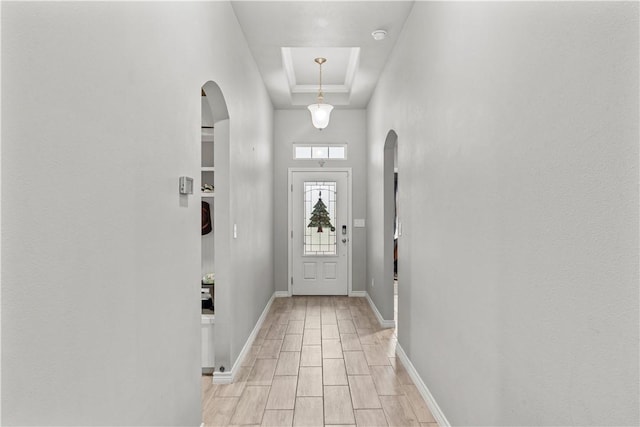 doorway featuring a tray ceiling and light hardwood / wood-style floors