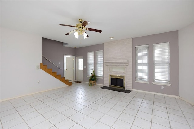 unfurnished living room featuring stairway, plenty of natural light, light tile patterned flooring, and a brick fireplace