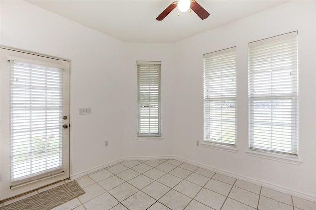 spare room featuring a ceiling fan, a healthy amount of sunlight, baseboards, and light tile patterned floors