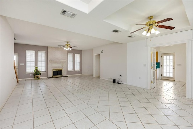 unfurnished living room with a ceiling fan, visible vents, a fireplace, and light tile patterned floors