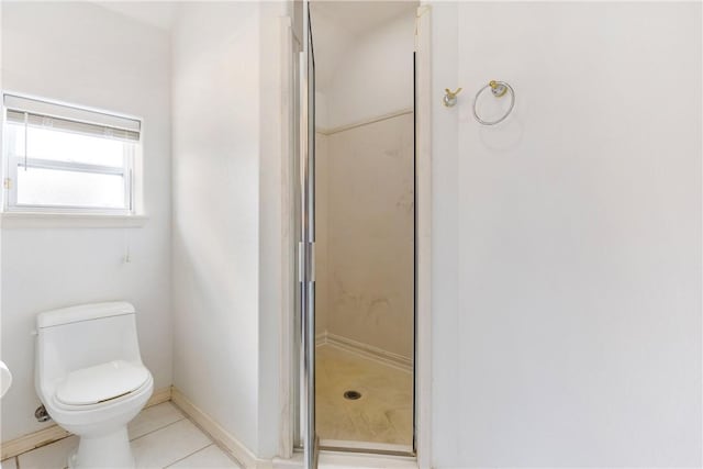 bathroom with a stall shower, baseboards, tile patterned flooring, and toilet