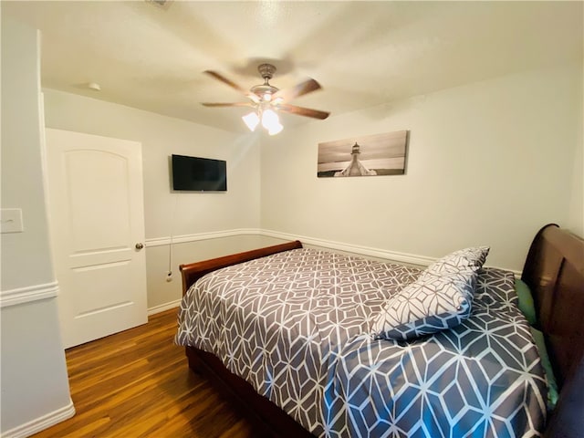 bedroom with dark hardwood / wood-style flooring and ceiling fan