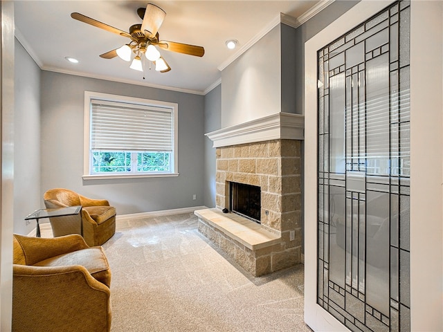 carpeted living room with ornamental molding, a stone fireplace, baseboards, and a ceiling fan