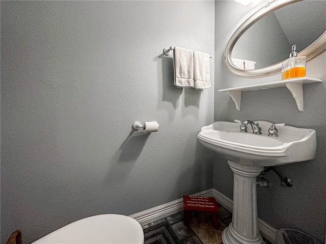 half bath with baseboards and toilet