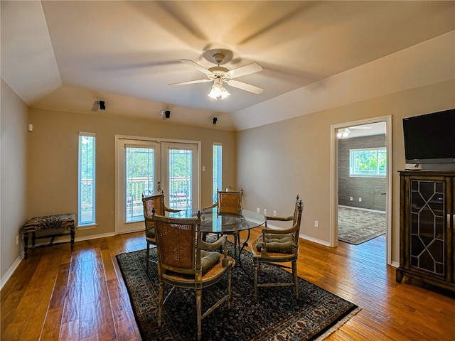 dining space featuring a healthy amount of sunlight, wood-type flooring, a tray ceiling, and baseboards