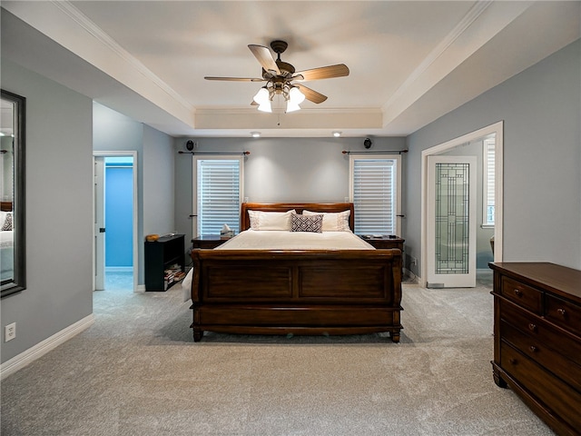 bedroom with ornamental molding, a tray ceiling, and light colored carpet