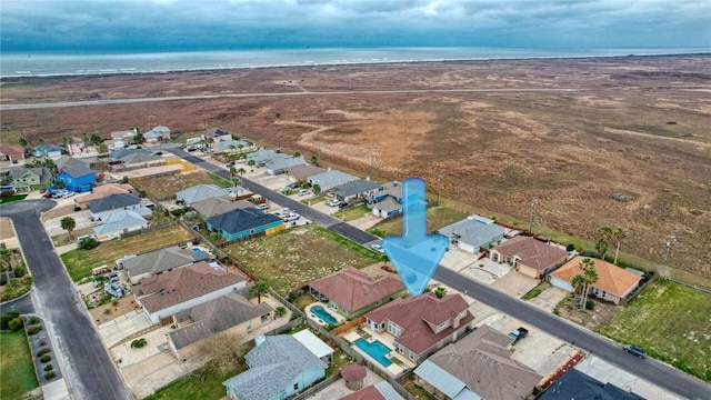 drone / aerial view featuring a water view, a view of the beach, and a residential view