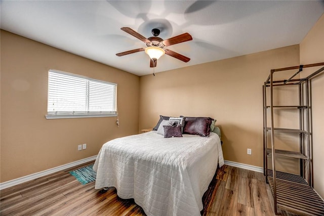 bedroom with ceiling fan, wood finished floors, and baseboards