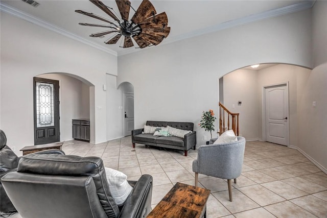 living area with light tile patterned floors, baseboards, arched walkways, and crown molding
