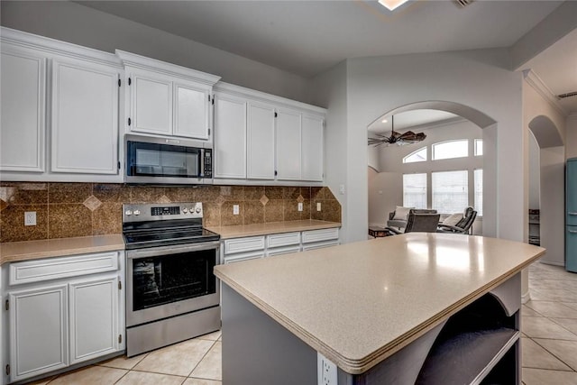 kitchen featuring tasteful backsplash, a ceiling fan, a kitchen island, appliances with stainless steel finishes, and white cabinetry