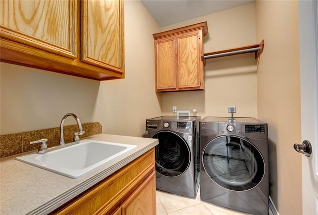 laundry area with cabinet space, light tile patterned floors, a sink, and washing machine and clothes dryer