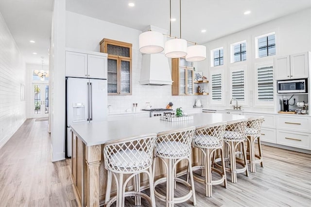 206 Lakeshore St, Port Aransas, TX 78373 - kitchen featuring built in appliances, custom range hood, a kitchen island, a sink, and light wood-style flooring