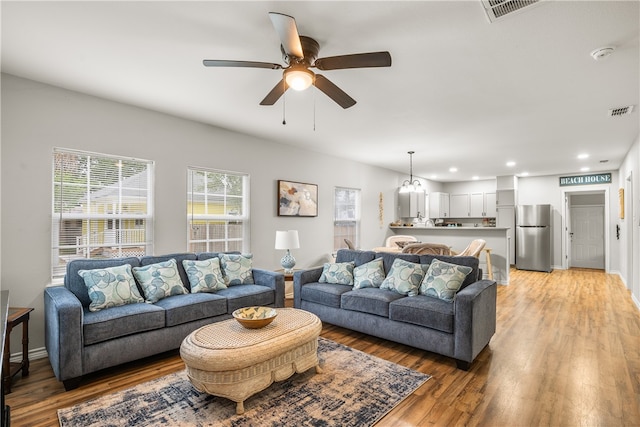 living room with ceiling fan with notable chandelier and wood-type flooring