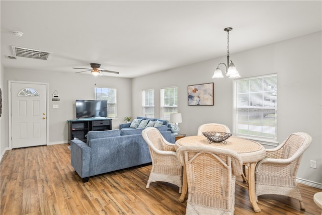 dining space with hardwood / wood-style flooring and ceiling fan with notable chandelier